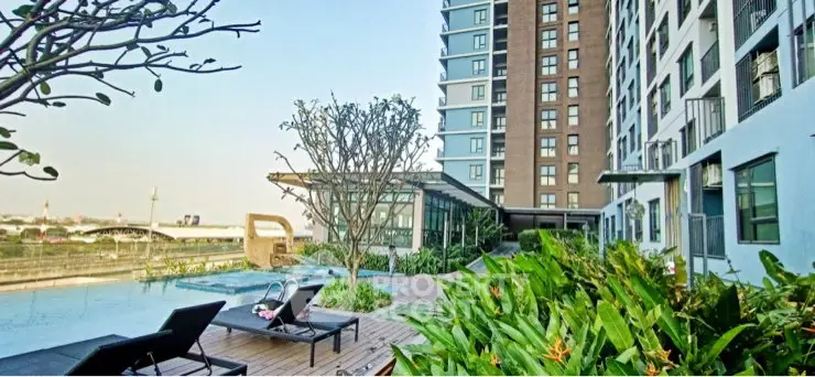 Modern apartment building with poolside relaxation area and lush greenery.