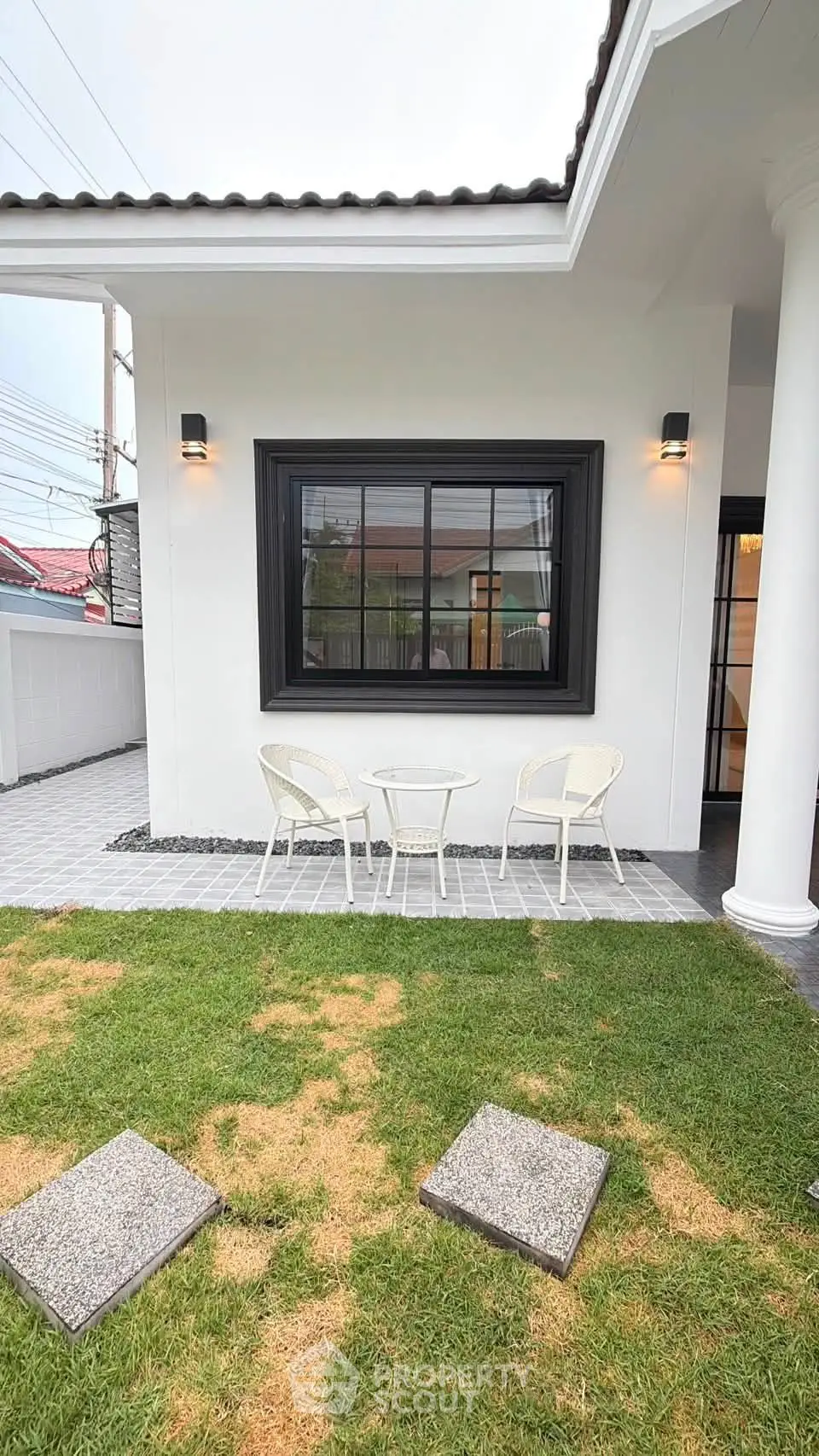 Charming modern house exterior with cozy patio and lush green lawn, perfect for outdoor relaxation.