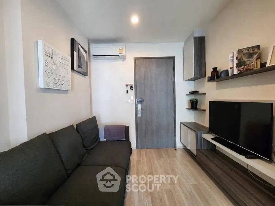 Modern living room with sleek furniture and wall-mounted TV in a cozy apartment.