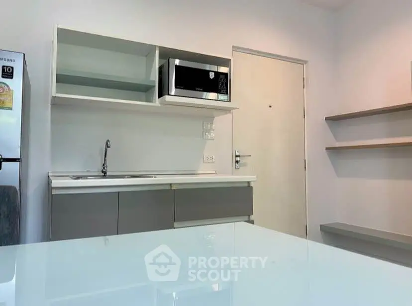 Modern kitchen with sleek cabinetry and built-in microwave in a minimalist apartment.