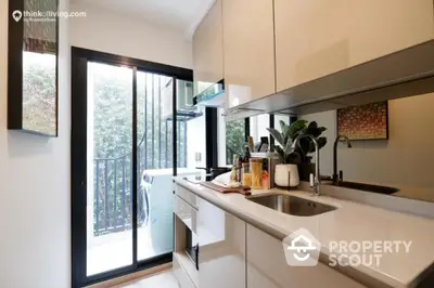 Sleek modern kitchen with stainless steel appliances, ample cabinetry, and a charming balcony with natural light streaming in, perfect for culinary enthusiasts.