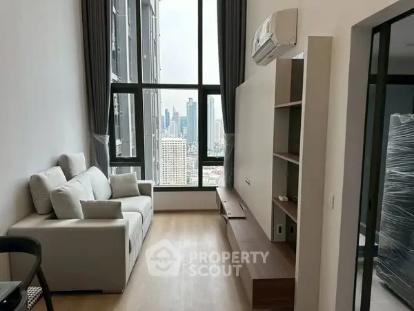 Modern living room with city view, featuring sleek furniture and large windows.