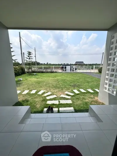 Charming garden view from a modern home entrance with stepping stones and lush greenery.