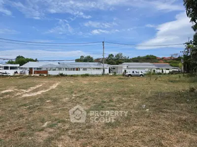 Expansive land with potential for development, featuring a white building and open sky view.