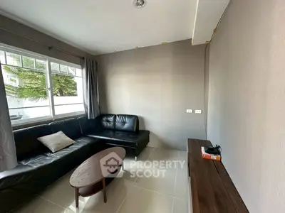 Cozy living room with modern black leather sofa and natural light