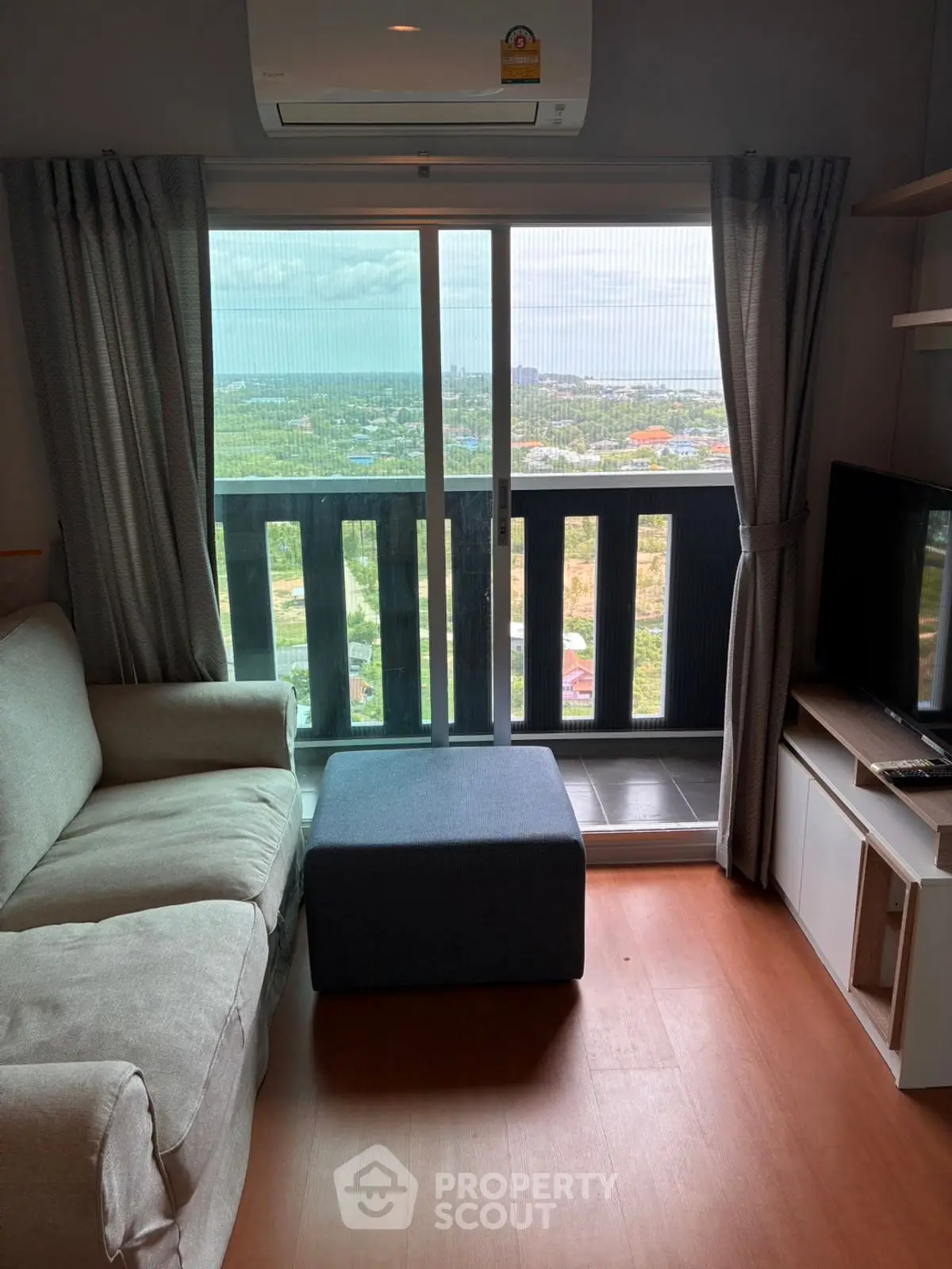 Cozy living room with sofa, TV, and balcony view in modern apartment.