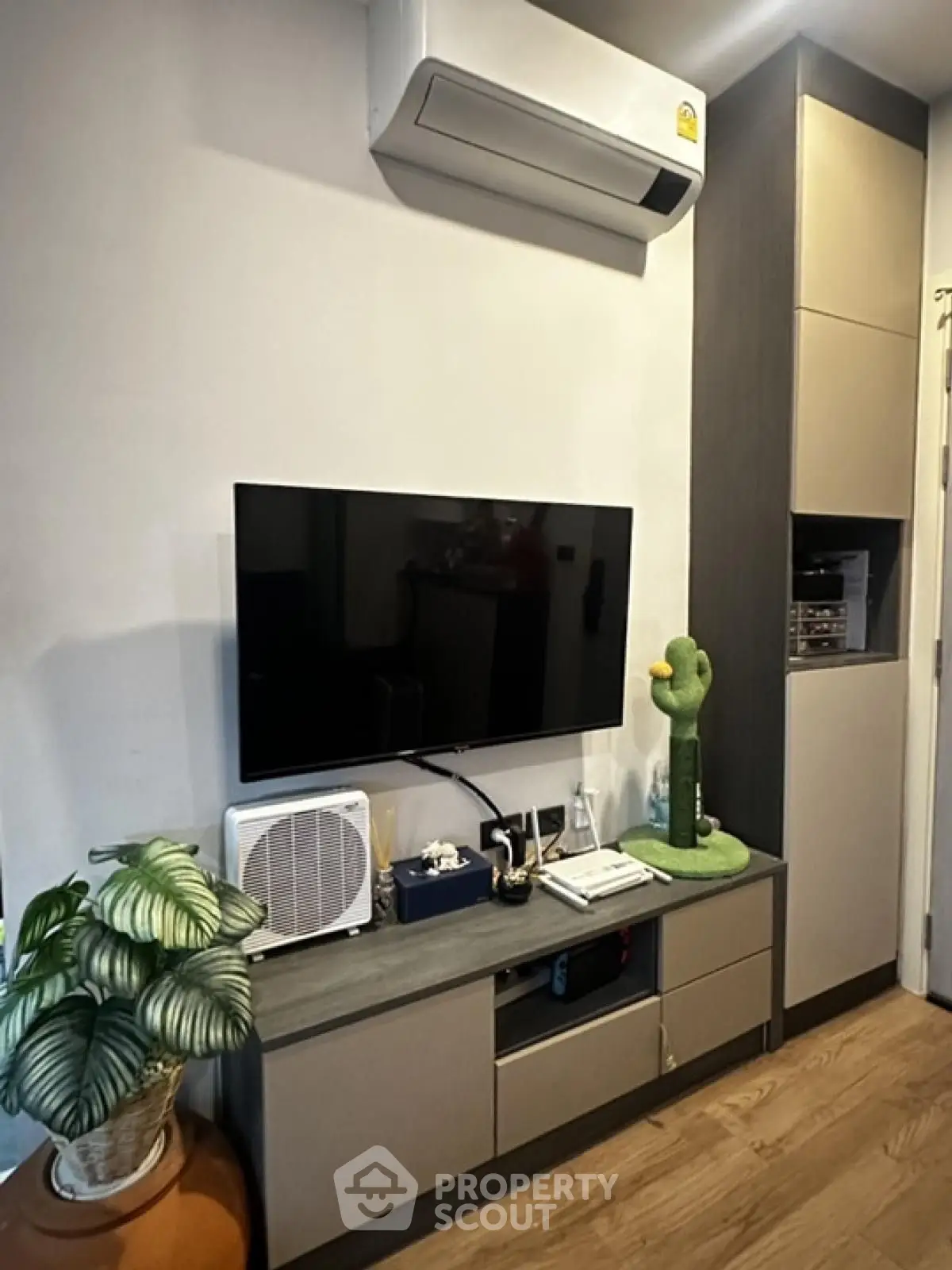 Modern living room with wall-mounted TV and air conditioner, stylish decor and storage.