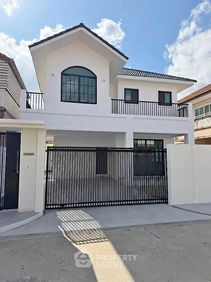 Modern two-story white house with black accents and spacious driveway under clear blue sky.