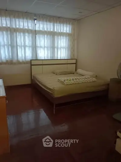 Cozy bedroom with large windows and wooden flooring, perfect for relaxation and comfort.