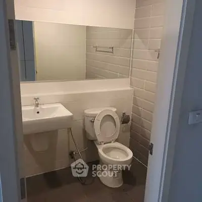 Modern bathroom with sleek design and neutral tiles, featuring a wall-mounted sink and toilet.