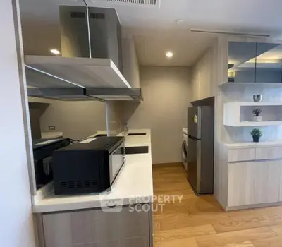 Modern kitchen with sleek appliances and wooden flooring in a stylish apartment.