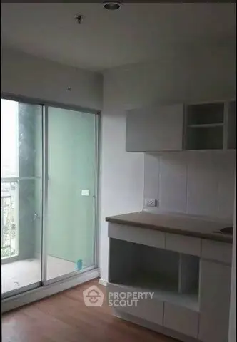 Modern kitchen with sliding glass doors leading to a balcony, featuring sleek cabinetry and hardwood floors.