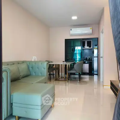 Modern living room with stylish green sofa and dining area in open layout apartment.