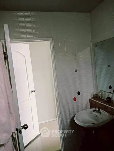 Cozy bathroom with modern sink and wall tiles, featuring a partially open door leading to a bright hallway.