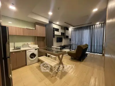 Modern open-layout living room with kitchen, featuring washing machine and stylish furniture.