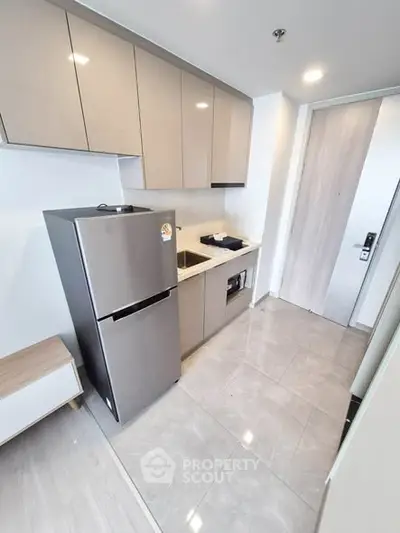 Modern kitchen with sleek cabinets and stainless steel fridge in a compact layout.