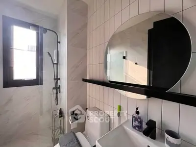 Modern bathroom with sleek fixtures and round mirror, featuring a stylish shower area and contemporary design.