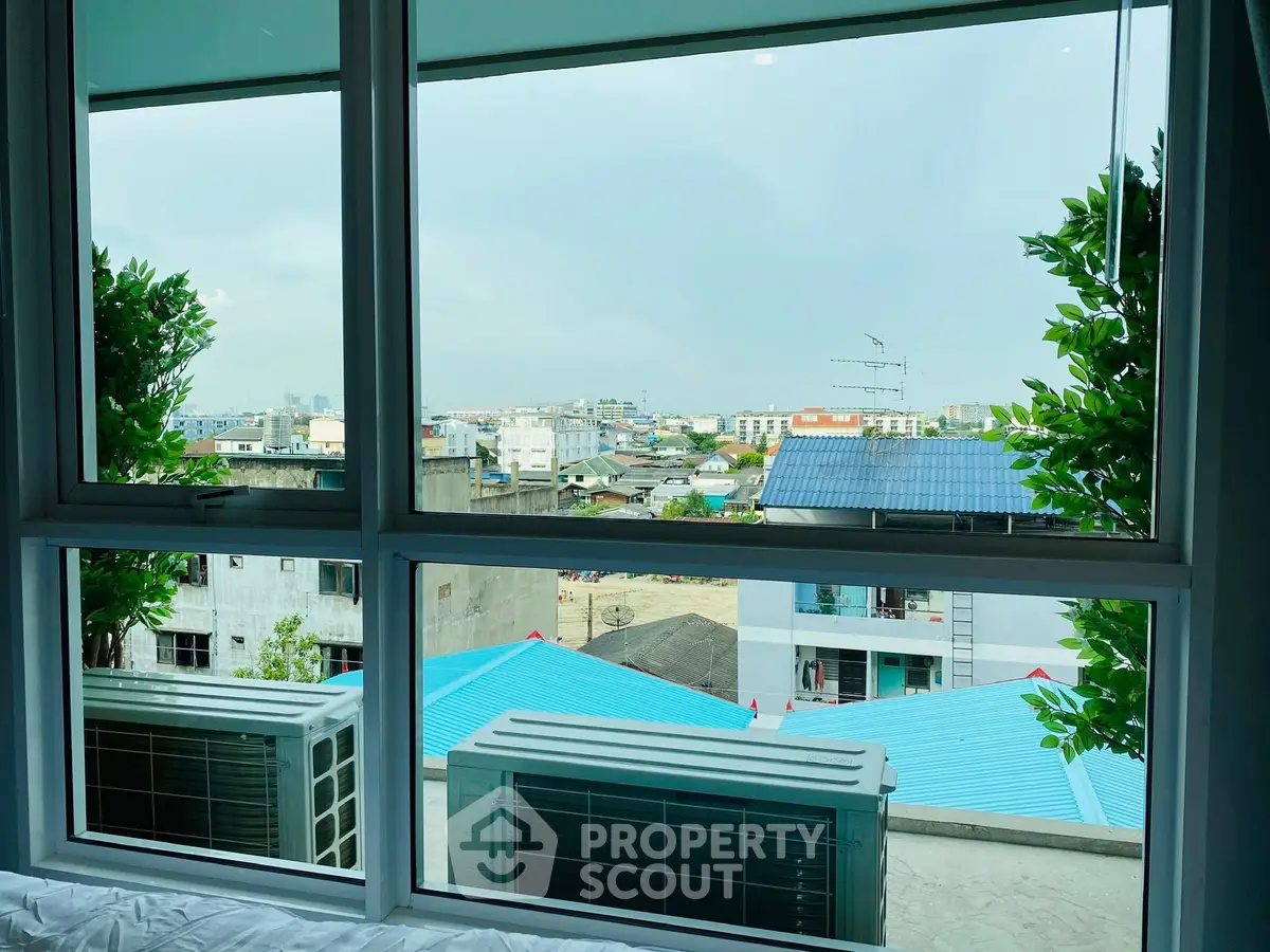 Stunning urban view from a modern apartment window with lush greenery.