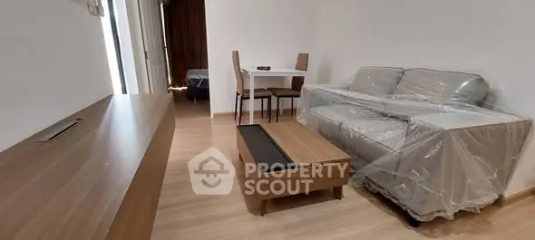 Modern living room with wooden flooring, sofa, and dining table in a cozy apartment setting.