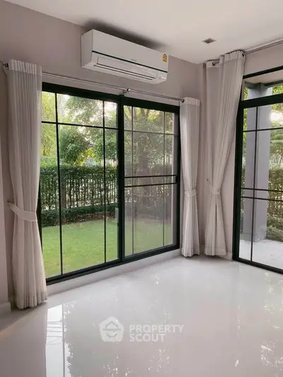 Bright living room with large windows and garden view, featuring sleek air conditioning unit.