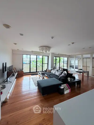 Spacious modern living room with large windows and stylish decor, offering a bright and inviting atmosphere.