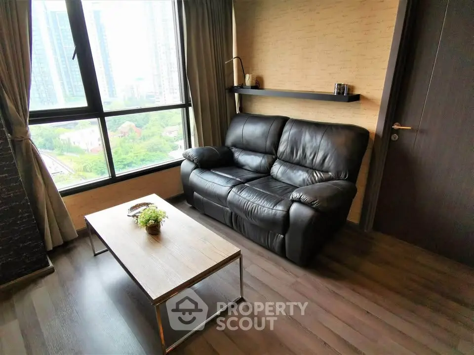 Cozy living room with black leather sofa and large window view
