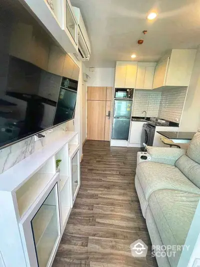 Modern living room with sleek kitchen, featuring hardwood floors and stylish furnishings.