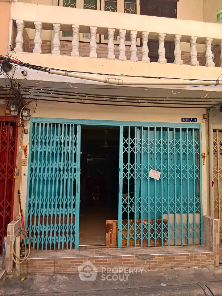 Charming urban property with blue sliding gate and balcony, ideal for residential or commercial use.