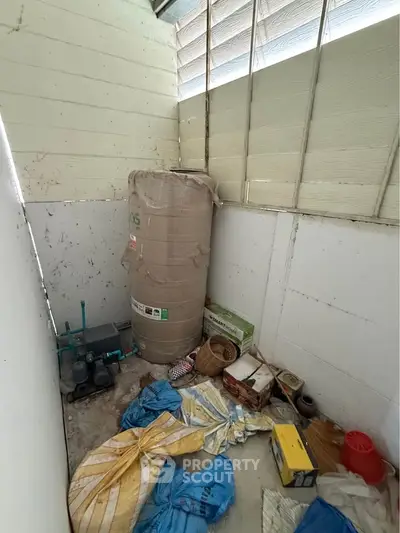 Storage room with water heater and miscellaneous items in a corner space.