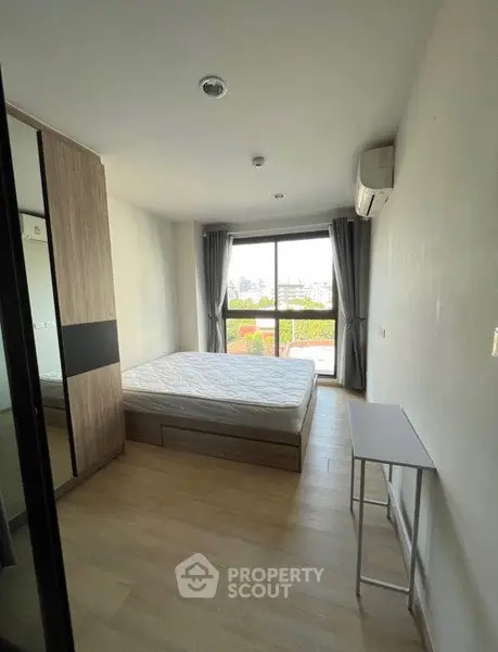 Modern bedroom with large window and minimalist furniture in a bright apartment.