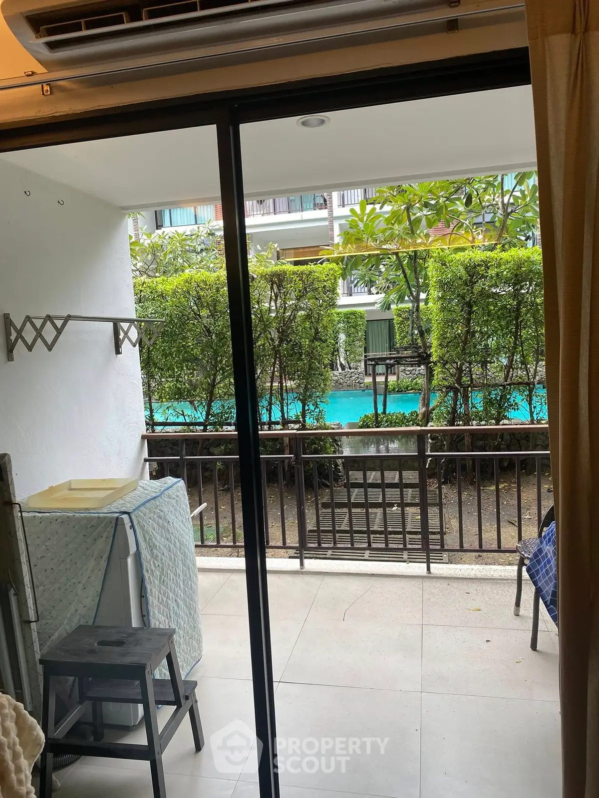 Charming poolside view from cozy balcony with lush greenery and modern amenities.