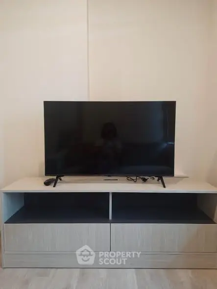 Modern living room with sleek TV on stylish wooden stand, perfect for entertainment.