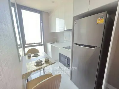 Modern kitchen with sleek appliances and dining area in bright apartment