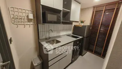 Modern compact kitchen with sleek appliances and stylish cabinetry in a cozy apartment.