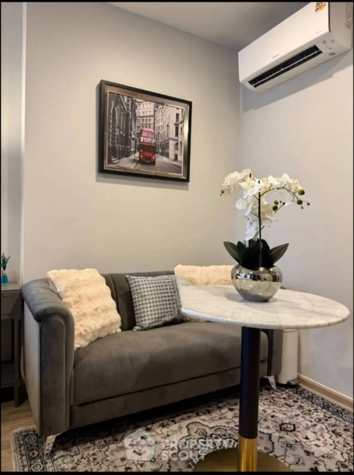 Cozy living room with elegant decor and air conditioning, featuring a plush sofa and stylish artwork.
