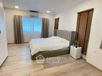 Spacious bedroom with modern decor and large windows for natural light.