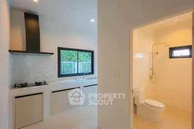 Modern kitchen with gas stove and adjacent bathroom in bright, airy home