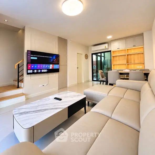 Modern living room with sleek furniture and wall-mounted TV in a stylish open-plan layout.