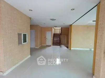 Spacious open-plan living area with elegant staircase and neutral decor