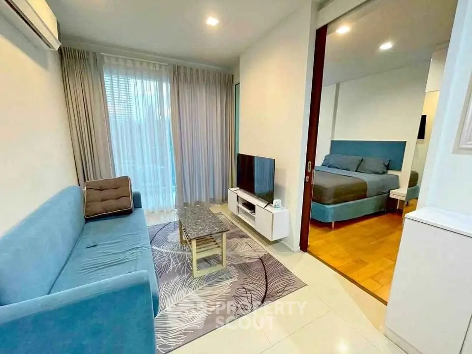 Modern living room with cozy sofa and TV, adjacent to a stylish bedroom with elegant decor.