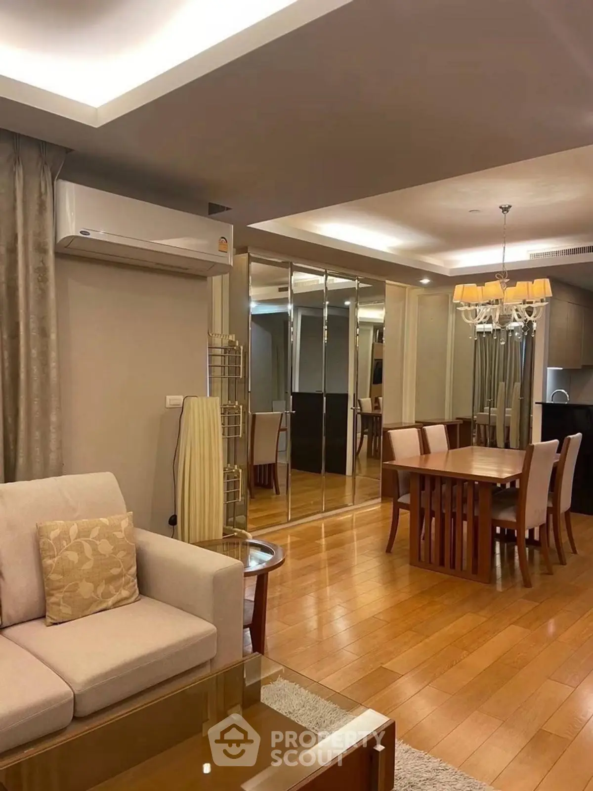Elegant living and dining area with modern decor and mirrored wall accents.