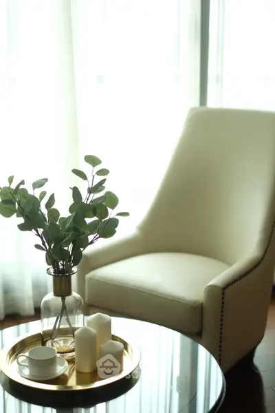 Elegant living room with stylish armchair and decorative centerpiece on glass table.