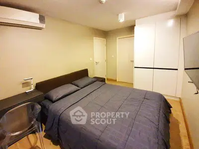 Modern bedroom with sleek design, featuring a comfortable bed, built-in wardrobe, and air conditioning.