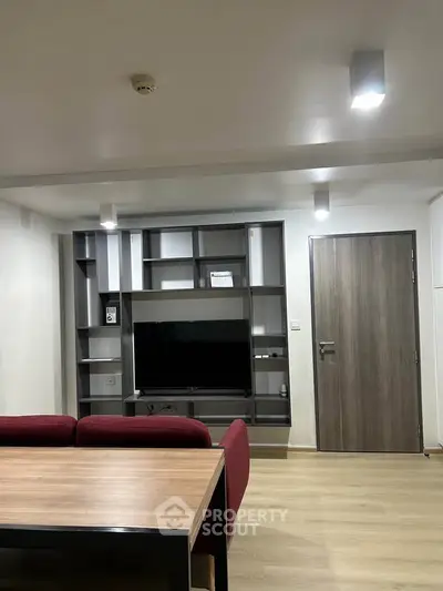 Modern living room with sleek shelving and flat-screen TV, featuring minimalist design and cozy seating.