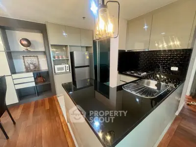 Modern kitchen with sleek black countertops and stainless steel appliances in a stylish apartment.