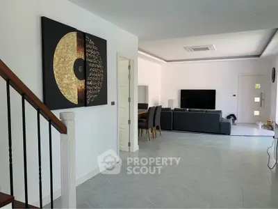 Spacious modern living room with elegant decor and open layout, featuring a large TV and stylish furniture.
