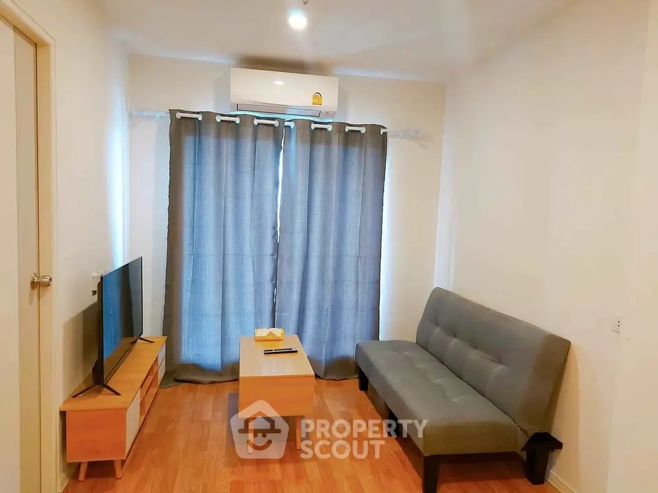 Cozy living room with modern sofa, TV, and air conditioning, perfect for relaxation.