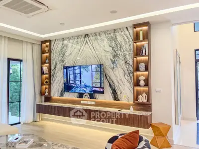 Luxurious living room with marble accent wall and built-in shelving, featuring modern decor and large windows.