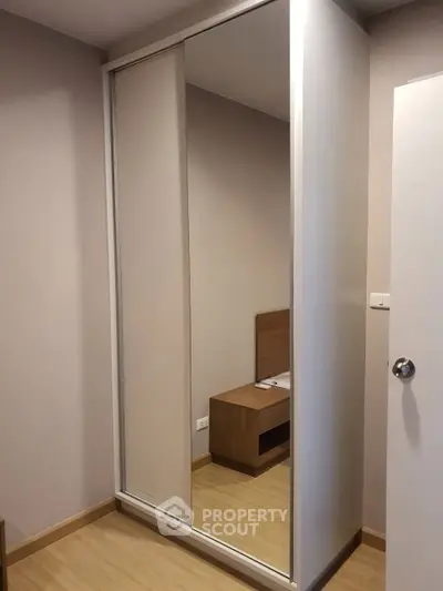 Modern bedroom with sleek sliding wardrobe and wooden flooring