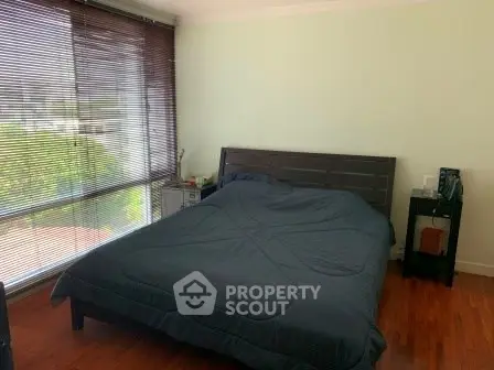 Spacious bedroom with large windows and wooden flooring, offering a serene and cozy atmosphere.